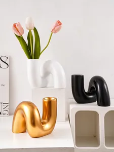 Gros plan de vases artistiques en résine en forme de U, textures mat et or