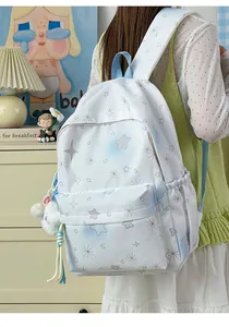 Detailansicht eines weißen Mädchenrucksacks mit Sternenmuster, Plüschtier und Quaste.