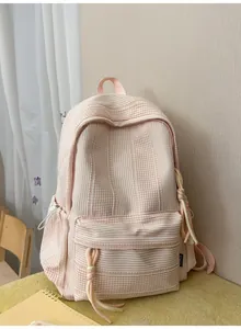 Detail of a pink and white plaid Korean school backpack with decorative rope accents