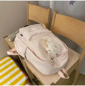 Close-up of pink and white striped school backpack with lace detail on wooden chair.