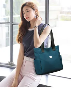 Asiatisches Model mit großer blaugrüner Oxford-Tote-Bag für minimalistischen Pendlerstil