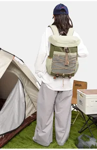 Woman carrying a stylish green and khaki outdoor hiking backpack at a campsite