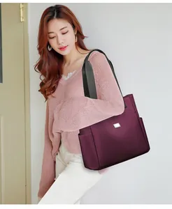 Asiatisches Model präsentiert eine große weinrote Oxford-Stoff-Einkaufstasche für den Alltag.