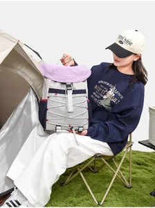 Lifestyle view of a minimalist outdoor hiking backpack held by a model at a campsite.