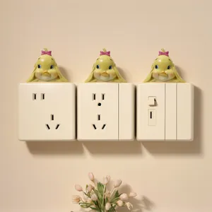 Macro view of cute yellow duck resin figurines decorating wall light switches