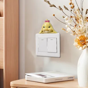 Macro detail of a cute handmade resin yellow duck figurine sitting on a light switch