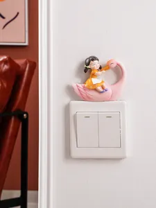 Detail view of a cute resin swan girl figurine mounted above a white light switch.