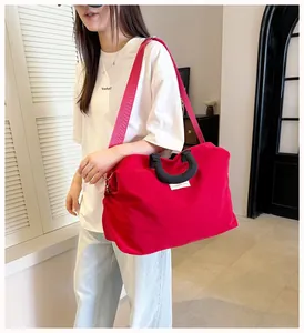 Borsa da viaggio rossa in nylon di grande capacità indossata in uno studio minimalista