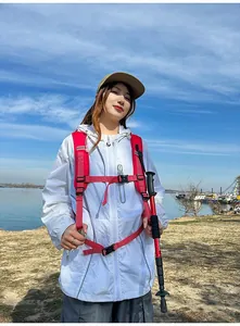 Donna che indossa giacca bianca e zaino da trekking rosa vicino a un lago panoramico