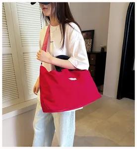 Borsa sportiva rossa capiente indossata da una modella in un ambiente informale