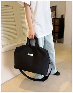 Persona che porta una grande borsa sportiva nera minimalista in una casa pulita