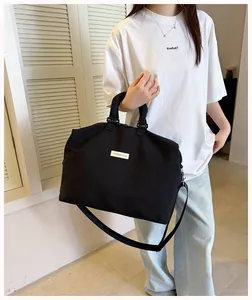 Grande borsa da fitness nera minimalista tenuta da una modella con tracolla lunga