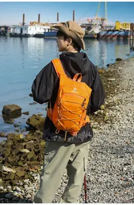 Vista posteriore di un uomo con uno zaino da trekking arancione leggero in riva al mare