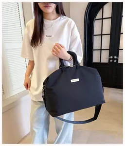 Foto lifestyle di una grande borsa da viaggio nera con tracolla e manici superiori