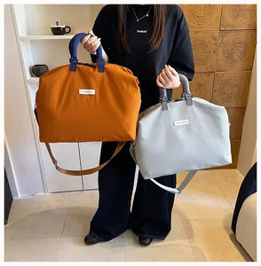 Grandi borse sportive minimaliste color arancio e grigio tenute da una modella di moda