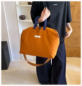 Grande borsa da viaggio sportiva arancione con manici blu in uno scatto lifestyle moda