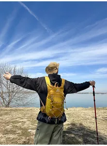 Una persona che indossa uno zaino da trekking giallo leggero di fronte a una vista sul lago.