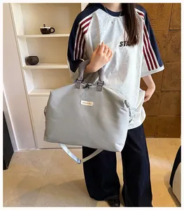 Modella con borsa da viaggio grigia minimalista in un ambiente di vita quotidiana.