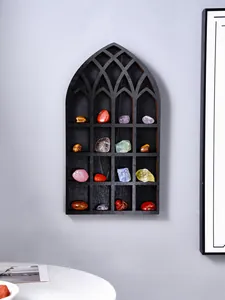 Detail of a gothic arch wooden display shelf for crystals on a grey wall.
