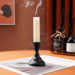 Elegant matte black iron candlestick holder with smoking white candle in home setting