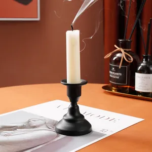 Close-up of matte black iron candlestick holder with smoke from a white candle