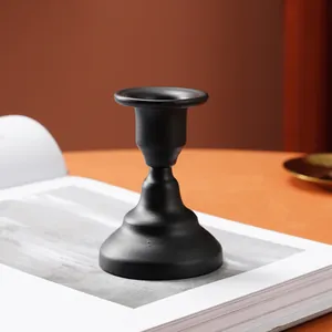 Detailed side view of a matte black iron candlestick holder on an open book for home decor