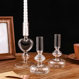 Primo piano di tre candelabri geometrici in vetro trasparente su un tavolo in legno