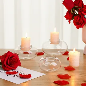 Moderne flachkugelige Glaskerzenhalter auf einem Holztisch mit Rosen und warmem Licht