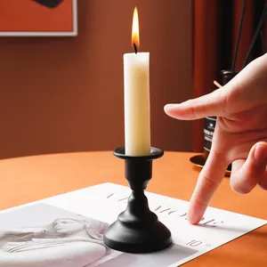 Elegant black metal candlestick holder with a lit white candle for romantic home decor