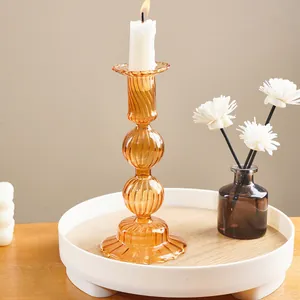 Close-up of amber striped glass candlestick holder with lit candle on tray
