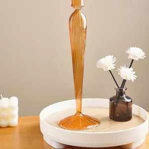 Detail view of a tall amber ribbed glass candlestick on a decorative white tray