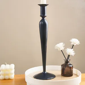 Close-up of a sleek black minimalist candlestick with props on a white wooden tray