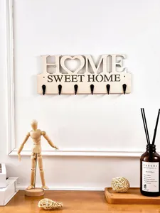 Detailansicht einer hölzernen HOME SWEET HOME Wandhakenleiste in gemütlicher Umgebung