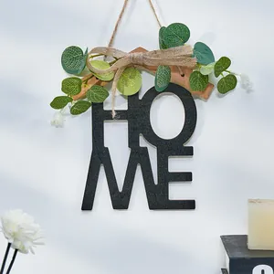 Vista detallada de una decoración de pared HOME de madera con hojas verdes y lazo