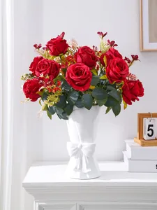 Lifelike red artificial roses arranged in a white decorative vase with a bow