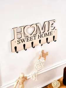 Nahaufnahme einer hölzernen Wandgarderobe 'HOME SWEET HOME' mit sechs schwarzen Haken.