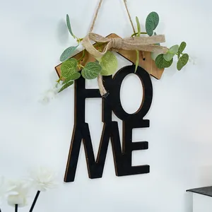 Vista detallada de una decoración de pared HOME de madera con vegetación falsa y lazo
