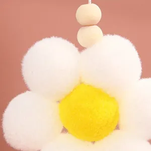 Close-up macro view showing texture of handmade white pom-pom flower pendant with beads