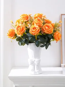 Detail view of artificial orange roses in a white bow ceramic vase for home decor