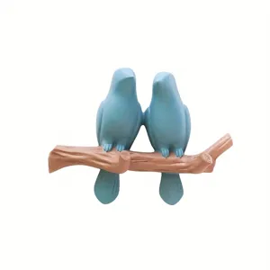 Detalle de un gancho de pared decorativo con dos pájaros azules para llaves.