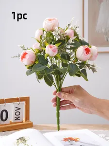 Close-up detailed view of an artificial pink peony bouquet held by hand at home