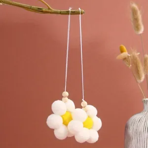 Detailed view of handmade white pom-pom flower pendants with wooden beads.