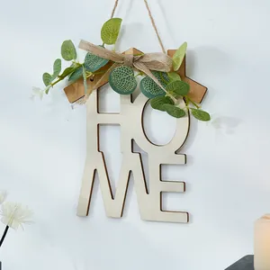 Vista detallada de la decoración de pared HOME de madera con hojas verdes y lazo