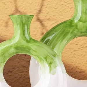 Dettaglio macro di pennellate verdi su vaso in resina bianca a forma di ciambella