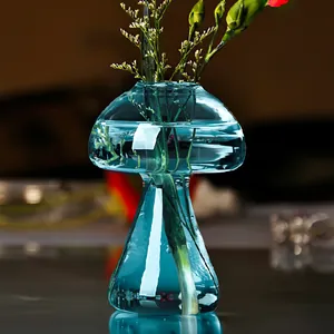 Vue détaillée du vase champignon en verre bleu décoration floral centre de table.