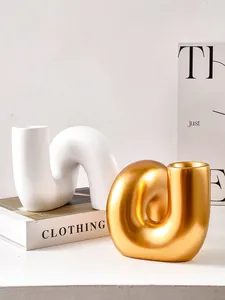 Gros plan de vases modernes en résine aux formes abstraites en blanc et or