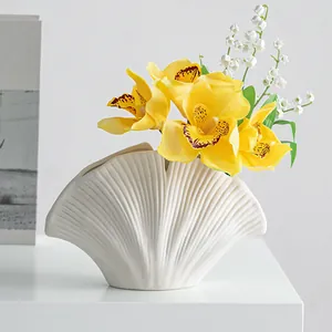 Detailopname van een moderne witte harsvaas in de vorm van een schelp met ribbeltextuur