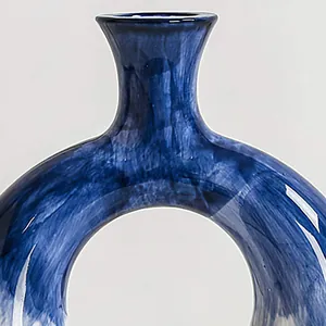 Dettaglio ravvicinato della trama blu dipinta a mano su un moderno vaso in resina a ciambella.