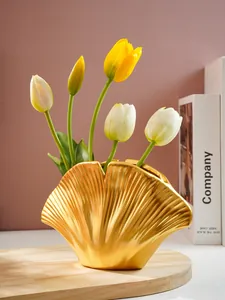 Close-up van gouden harsvaas in schelpvorm met elegante geplooide textuur en tulpen