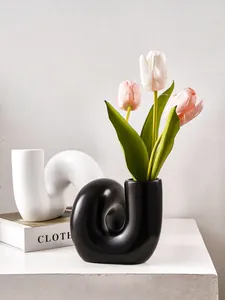 Vase créatif en résine courbé avec des tulipes roses sur une surface blanche